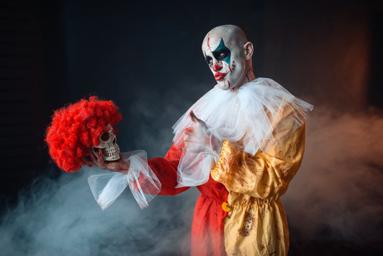 Mad bloody clown holds human skull in red wig - Powered by Adobe