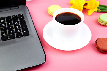Woman or feminine workspace with notebook, coffee, macarons and flowers