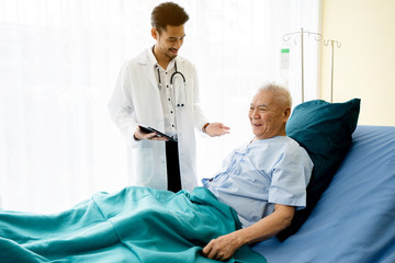 Asian Doctor is standing by explain the treatment information via the tablet to an elderly patient...