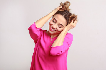 Fototapeta premium Funny girl playing with her hair over gray background