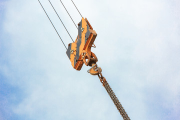 Crane load hook against the sky with trails and chain.