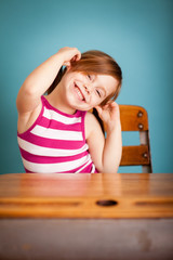 Silly Little Girl Sitting in School Desk