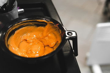 Orange, yellow Hair dye in black bowl. Hair coloring, beauty salon concept background