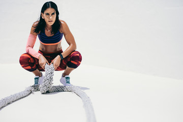 Fitness woman relaxing after workout holding battle ropes