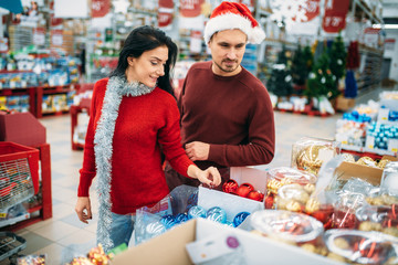 Young couple chooses christmas tree toys in shop