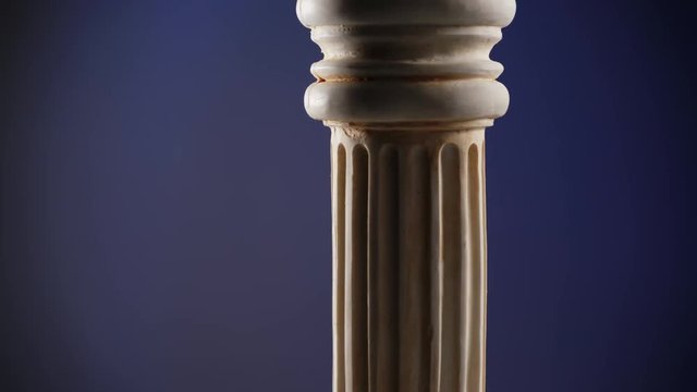 Single ancient greek column rotating slowly on dark blue background