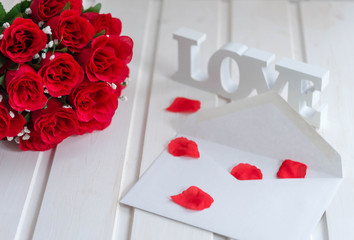 white letters love, white envelope, rose blossoms and bouquet red roses textile