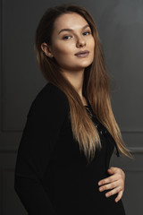 Fototapeta premium Portrait gorgeous young pregnant woman touching gently with hand