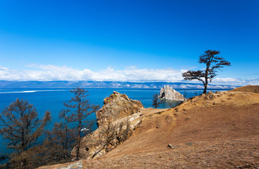 Fototapeta premium Lake Baikal. Olkhon Island in May day. View of the Small Sea Strait, the famous Shamanka Rock and the tree of desires on a sunny day. Beautiful spring landscape