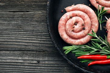 Homemade natural sausage. Sausage ring before cooking with spices and herbs on a wooden background. Top view.