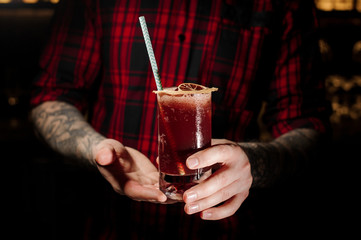Barman holding a glass of cold fresh juicy berry alcoholic cocktail