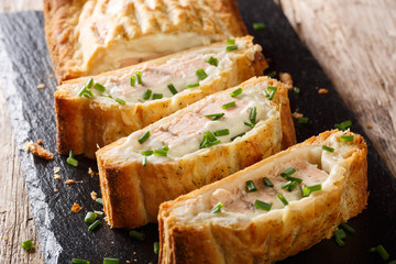 Sliced puff pastry pie stuffed with salmon and cheese close-up. horizontal