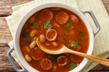 Polish cuisine Breton beans with sausage close-up in a pan. Horizontal top view