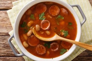 Delicious Polish dish of Breton beans with sausage close-up in a saucepan. horizontal top view