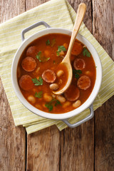 Rustic style Polish Breton beans with sausage close-up in a saucepan. Vertical top view