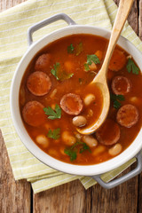 Polish cuisine Breton beans with sausage close-up in a pan. Vertical top view