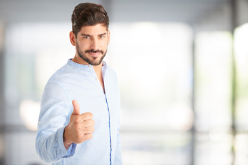 Successful in life. Shot ot a young man giving thumbs up while looking at camera and smiling.