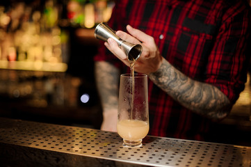 Fototapeta na wymiar Bartender pouring a portion of alcoholic drink using jigger