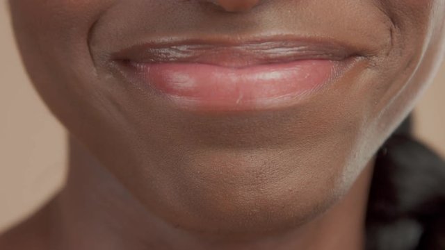 macro mauth of black mixed race woman smiling, sending kiss and movingt her tongue from side to side