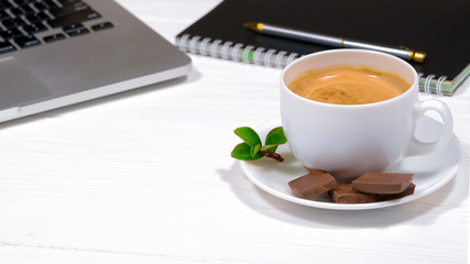 hot coffee with chocolate and a laptop on a wooden place