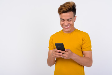 Portrait of happy young Asian man using phone against white background