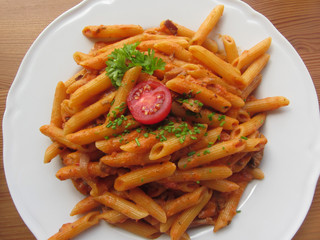 Italian penne pasta with tomato sauce, cream, mushrooms, bacon and chives . View from above