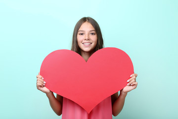 Young girl holding red paper heart on mint background