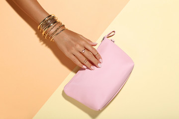 Female hand with bracelets and handbag on colorful background