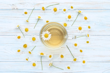 Cup of tea with chamomile flowers on wooden table