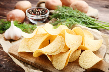 Potato chips with garlic and green dill on wooden table