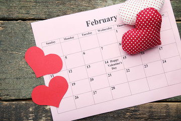 Red hearts with february calendar on wooden table