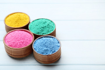 Colorful holi powder in bowls on wooden table