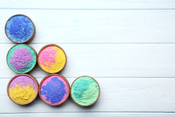 Colorful holi powder in bowls on wooden table