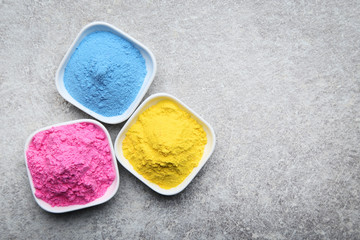 Colorful holi powder in bowls on grey background