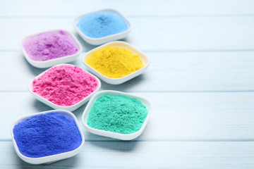 Colorful holi powder in bowls on wooden table