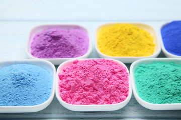 Colorful holi powder in bowls on wooden table