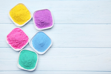 Colorful holi powder in bowls on wooden table