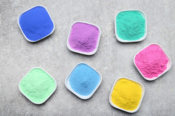 Colorful holi powder in bowls on grey background