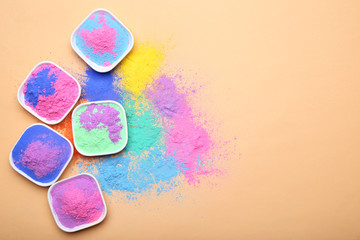 Colorful holi powder in bowls on beige background
