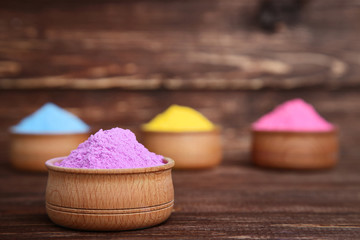 Colorful holi powder in bowls on brown wooden table