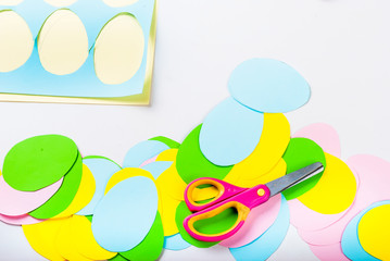 Many Easter paper eggs,  scissors and Sheets of colored paper.