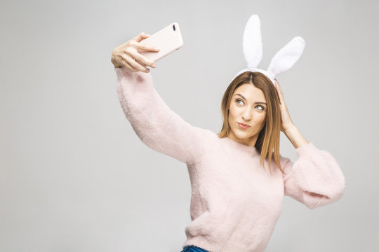 Close up studio photo portrait of nice pretty lady looking at camera wearing fluffy bunny ears taking making selfie isolated over white background.