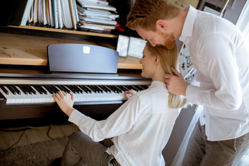 Loving young couple playing piano