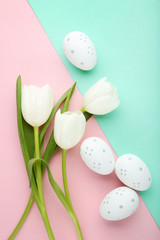 White tulips with easter eggs on colorful background