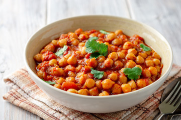 Spicy Chickpea curry Chana Masala in bowl on wooden table. Traditional Indian dish. Selective focus.
