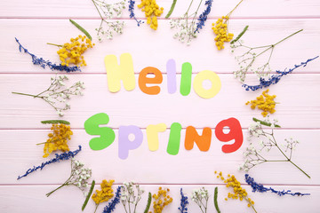 Inscription Hello Spring with flowers on wooden table