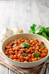 Spicy Chickpea curry Chana Masala in bowl on wooden table. Traditional Indian dish. Selective focus.