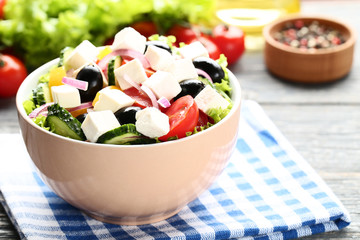 Vegetable salad in bowl with napkin on wooden table