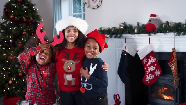 Portrait Of Children Wearing Festive Jumpers And Hats Celebrating Christmas At Home Together