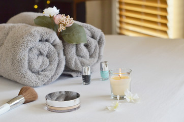 Beauty products with towels, flowers and candle.